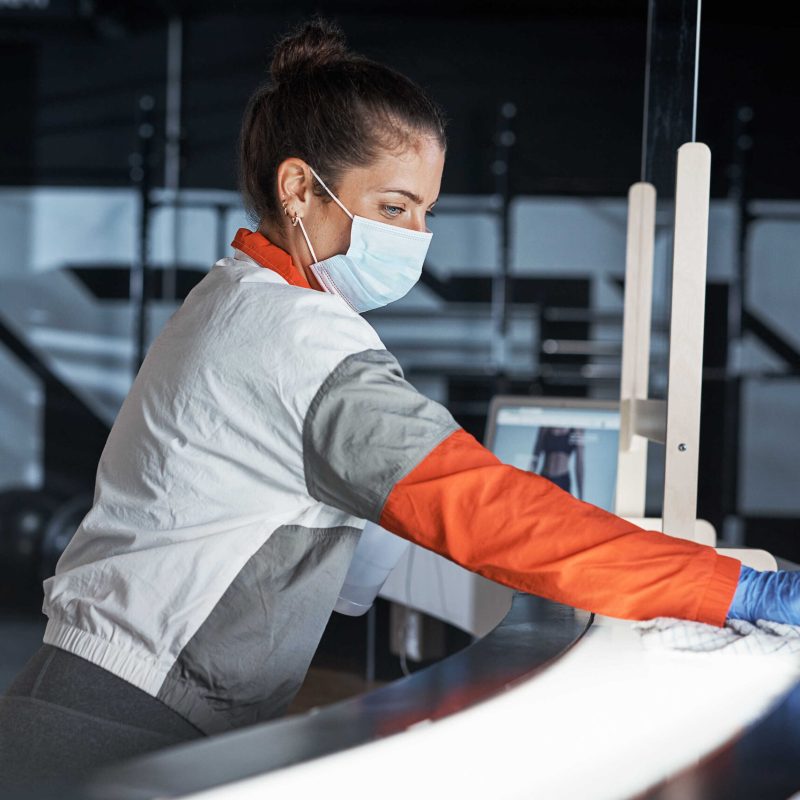Shot of a young woman cleaning the reception desk in a gym.